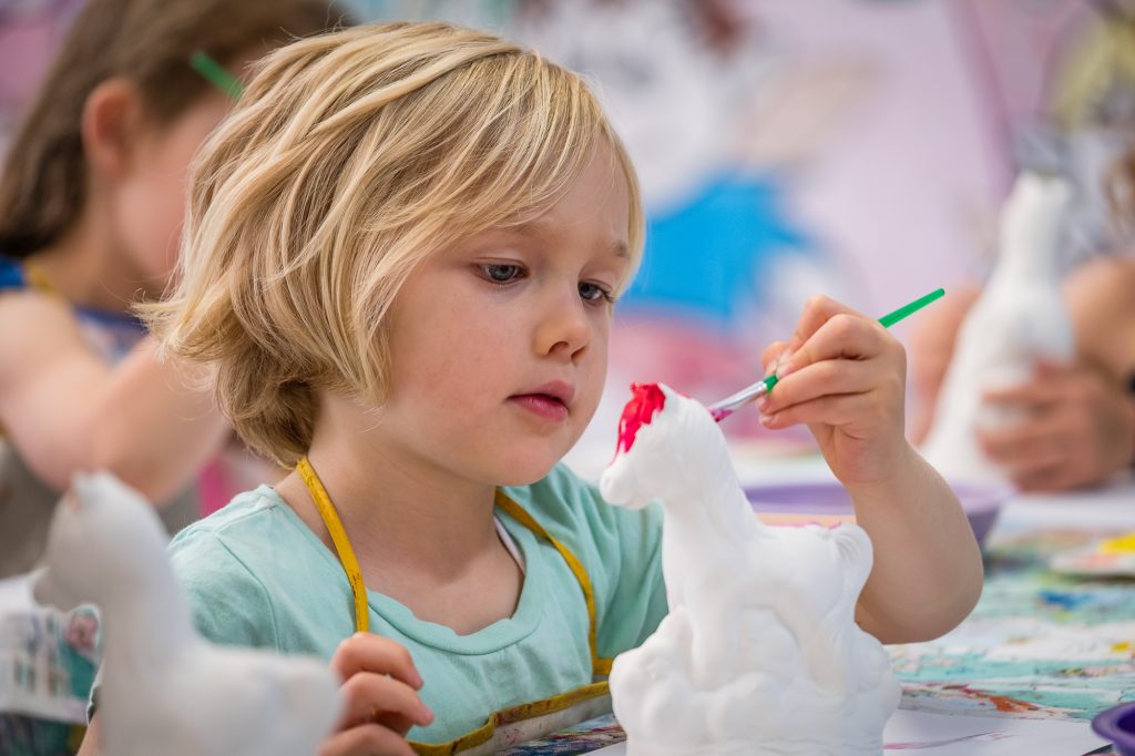 Arty paints a plaster pony with all her concentration. Most beautiful child in the world.